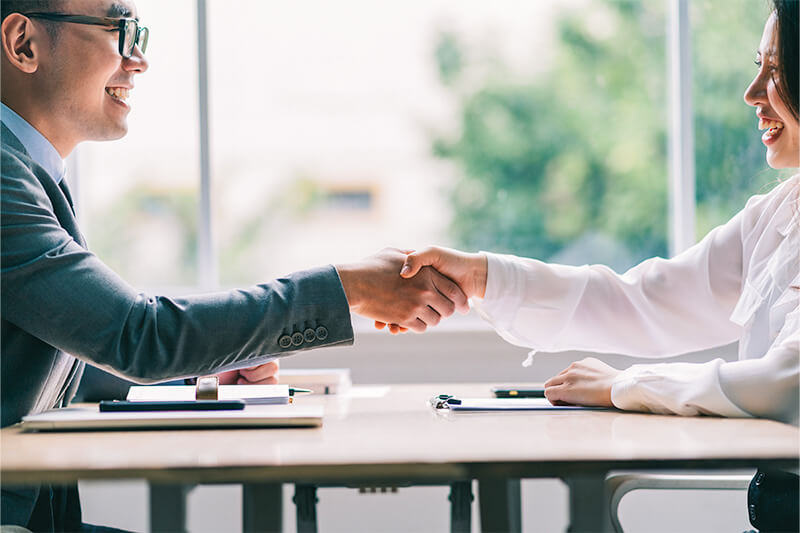 Two business professionals in suits having a discussion during a job interview in an office setting.
