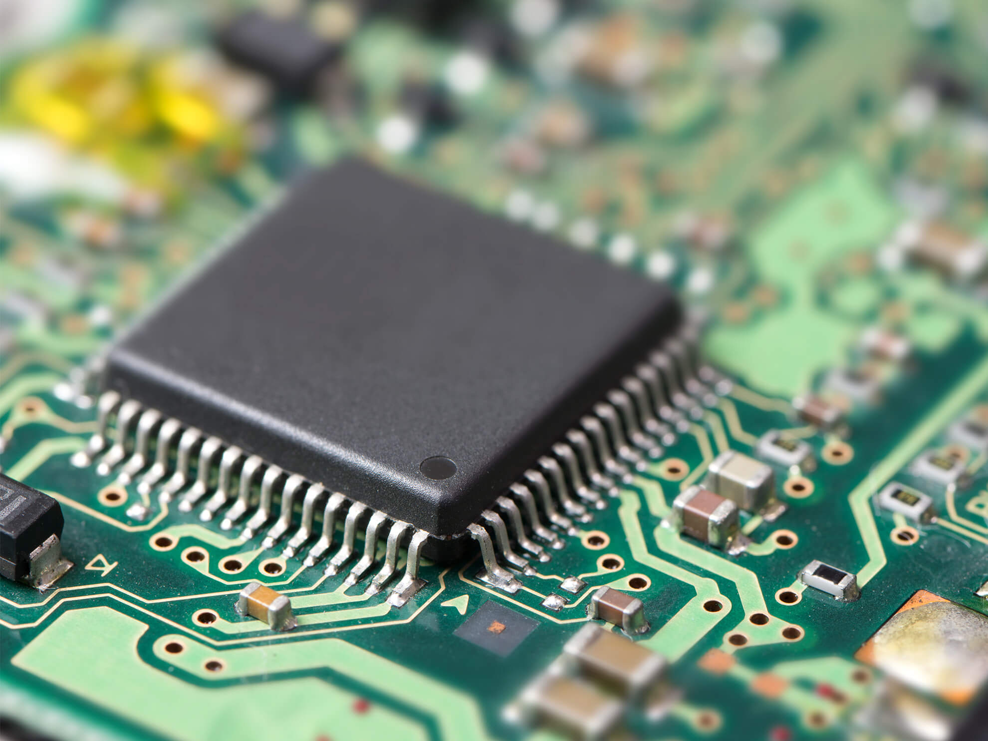 Close-up view of an integrated circuit on a green PCB.