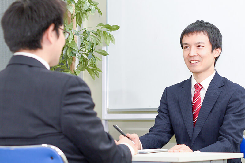 スーツ姿の男性が面談で笑顔を見せている様子。