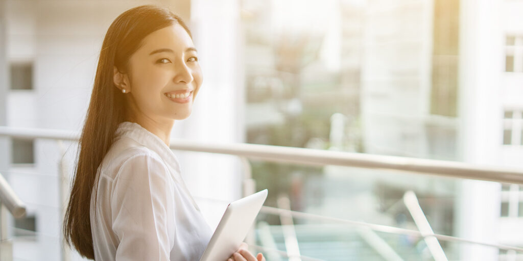 タブレットを持って明るく微笑んでいる女性